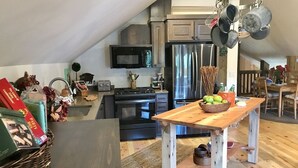 Una cocina moderna con una mesa de madera, electrodomésticos de acero inoxidable y un perchero para ollas.