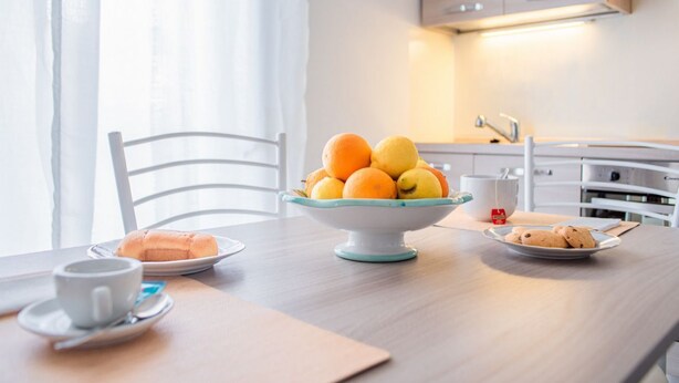 A breakfast table with a bowl of fruit, a plate of cookies, and a cup of coffee.
