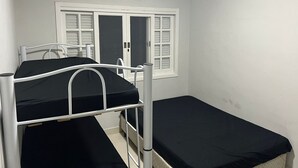 Una habitación con dos literas, una ventana con contraventanas y un aire acondicionado instalado en el techo.