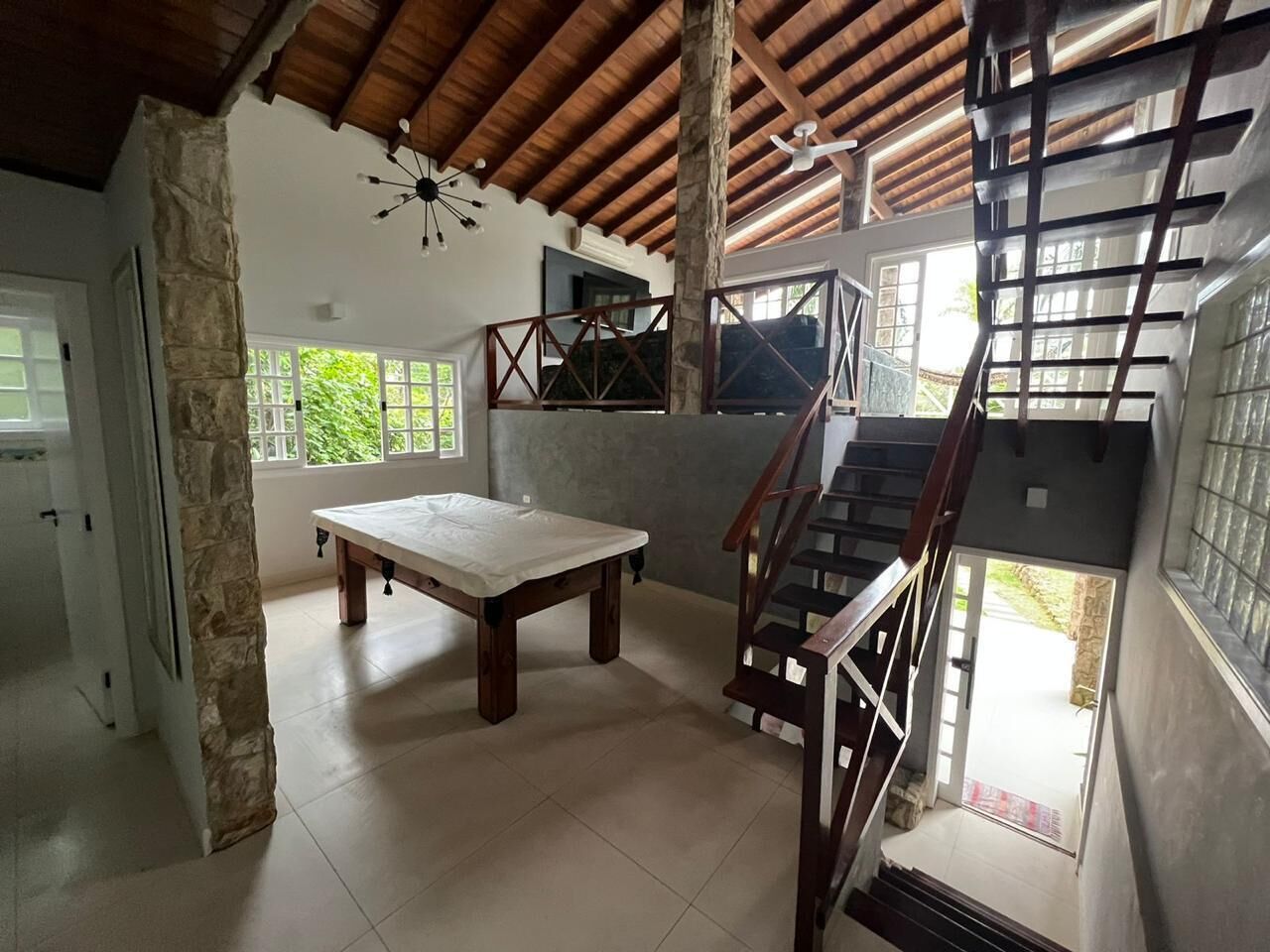 A spacious room with a high ceiling, a wooden staircase, and a large table.