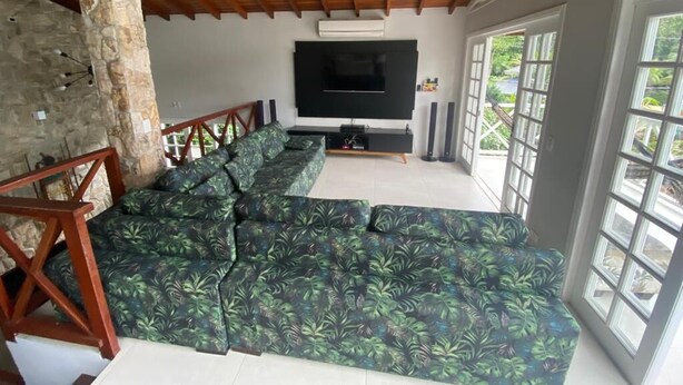 Un salón amplio con un sofá modular grande, un televisor de pantalla plana y un ventilador de techo.