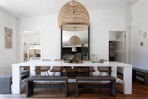 A modern dining area with a white table, wicker chairs, and a large woven pendant light. - Fingal House-Ultimate Escape for Groups, Families & Retreats (Fingal)