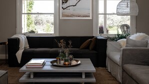 A living room with a dark-colored sofa, a white coffee table with decorative items, and a framed picture on the wall. - Fingal House-Ultimate Escape for Groups, Families & Retreats (Fingal)