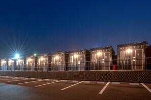 A row of well-lit, numbered hotel rooms with a fence in front. - HOTEL R9 The Yard Ami (Ami)