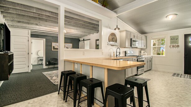 Una cocina moderna con una isla central, taburetes de bar y un letrero que dice 'FARM FRESH LEMONS'.