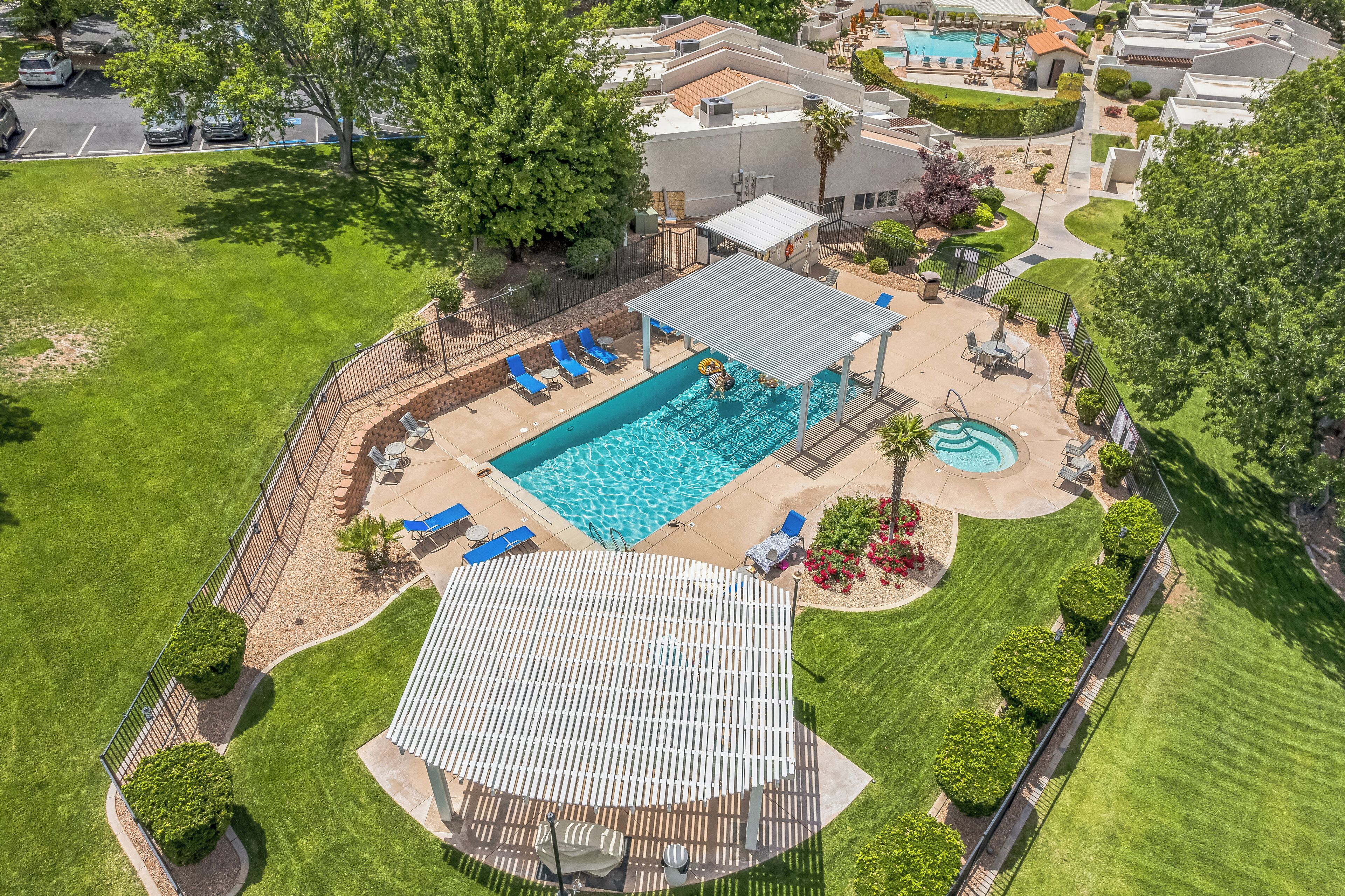 An aerial view of a residential property with a swimming pool, sun loungers, and a covered patio area.