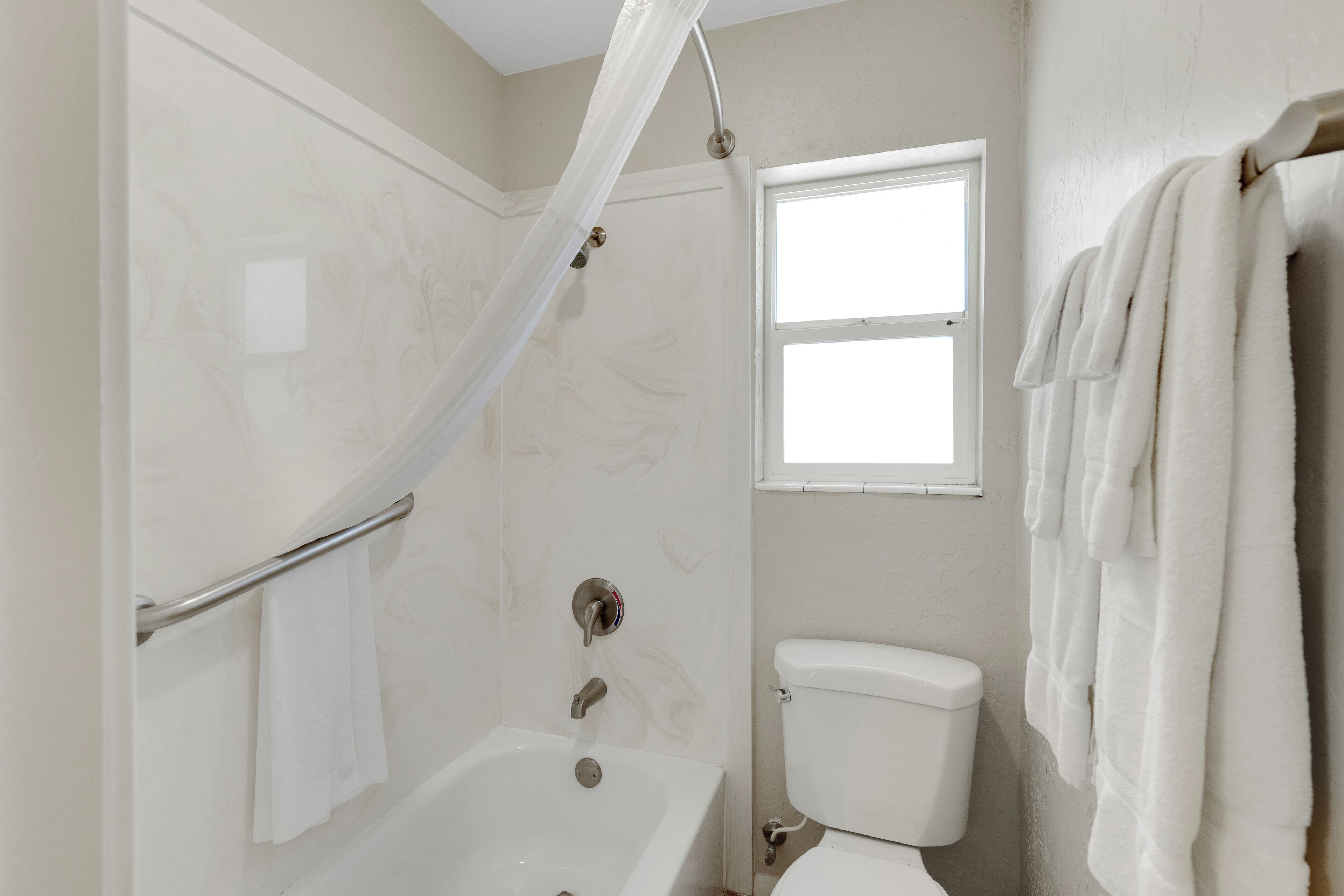 Een badkamer met een bad, toilet en een raam.