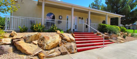 A building with a covered porch, a staircase with red steps, and a sign indicating a business office.