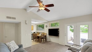 A living room with a gray sofa, a ceiling fan, and a dining area with a table and chairs. - Villas at Southgate (St. George)