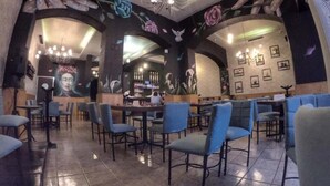 En restaurang med blå stolar, en bardisk och blommotiv på väggarna.