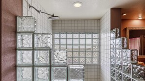 A bathroom with a glass block shower enclosure, a tiled wall, and a mirror.