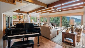 A spacious living room with a grand piano, comfortable seating, large windows, and a balcony with a mountain view. - Spacious Luxury Home Close to Downtown and Ski, Private Hot Tub, Amazing Views (Durango)