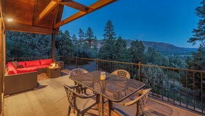 A covered outdoor seating area with a table and chairs, a sofa, and a small table with a candle. - Spacious Luxury Home Close to Downtown and Ski, Private Hot Tub, Amazing Views (Durango)