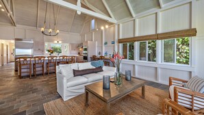 Una cocina amplia con comedor, una sala de estar con sofá y mesa de centro, y ventanas grandes con vistas a zonas verdes.
