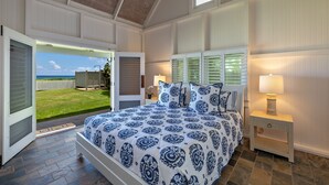 Un dormitorio con una cama grande, una mesita de noche, una ventana con persianas y vistas al exterior.