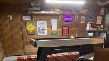 A room with a pool table, a red striped rug, and a wooden wall with various signs and decorations.