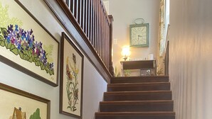 A wooden staircase with a handrail, leading to a landing with a table and a clock.