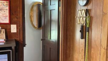 Un interior de madera con puerta, espejo, reloj y perchero en la pared.