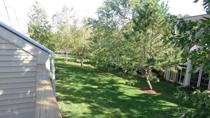 A backyard with a wooden deck, a lawn, and several trees. - Gorgeous 3 Bedroom Townhouse, Bethany Beach, steps from pool and fitness center (Bethany Beach)