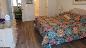 A bedroom with a bed, a dresser, and a door leading to another room. - Gorgeous 3 Bedroom Townhouse, Bethany Beach, steps from pool and fitness center (Bethany Beach)