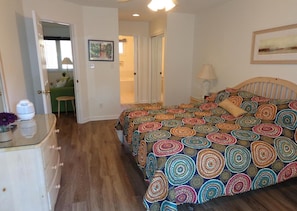 Une chambre à coucher comprenant un lit, une commode et une porte donnant sur une autre pièce.
