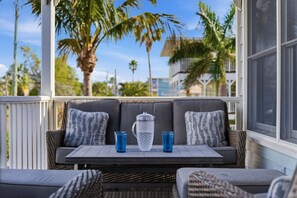 A covered outdoor seating area with a table, two chairs, and a large pitcher.