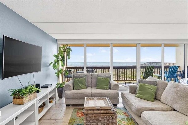 A modern living room with a flat-screen TV, a sofa, a coffee table, and a potted plant.