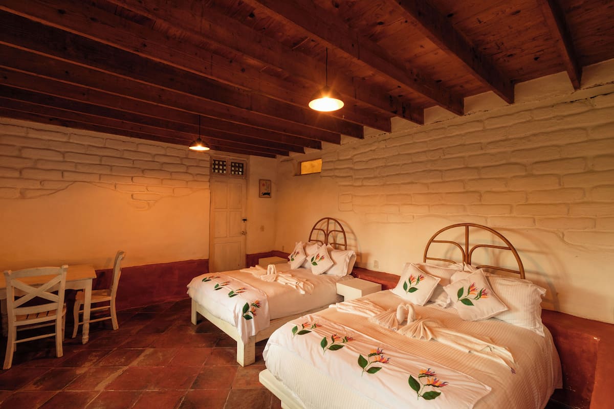 Habitació amb dos llits, sostre de fusta i paret de rajola.