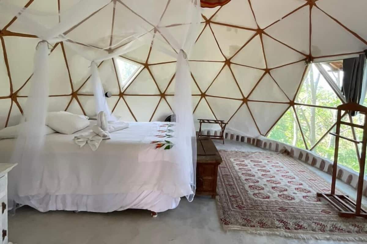 Una habitació tipus tenda amb un llit, una banca i una catifa amb dibuixos.