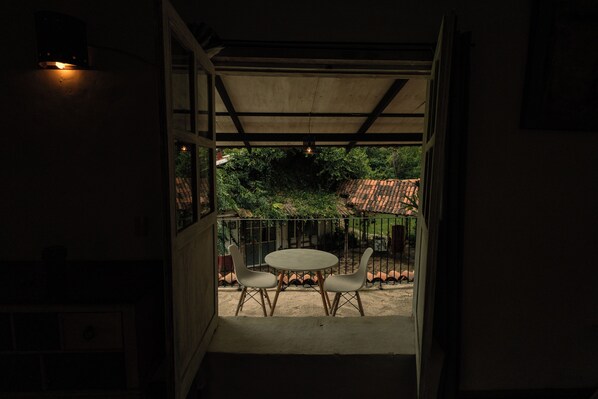An open doorway leading to a covered outdoor area with a table and two chairs.