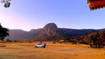 Un coche blanco estacionado en un campo con una montaña al fondo.