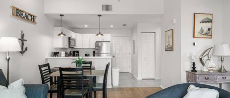 Una sala de estar moderna con comedor, cocina y un pasillo que conduce a un dormitorio.