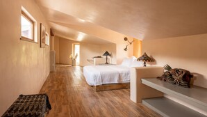 Une chambre à coucher comprenant un lit, des tables de chevet, une commode, une fenêtre et un escalier.