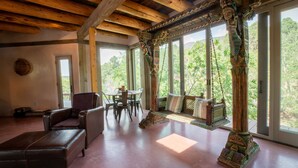 Une pièce spacieuse dotée d’une grande fenêtre, d’un plafond en bois, d’un canapé, d’une table et d’un pilier décoratif.