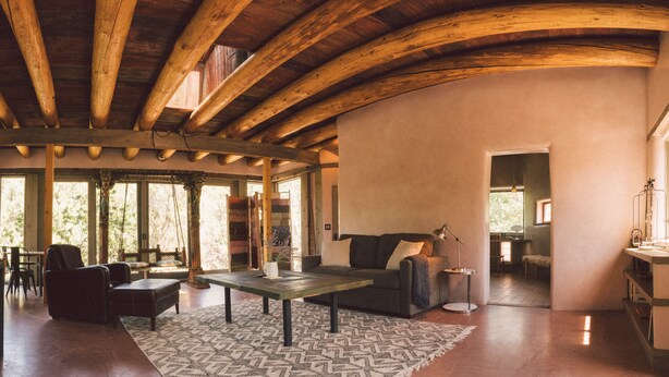 Un vaste espace de vie doté d’un plafond en bois, d’un canapé, d’une table basse et d’un tapis à motifs.