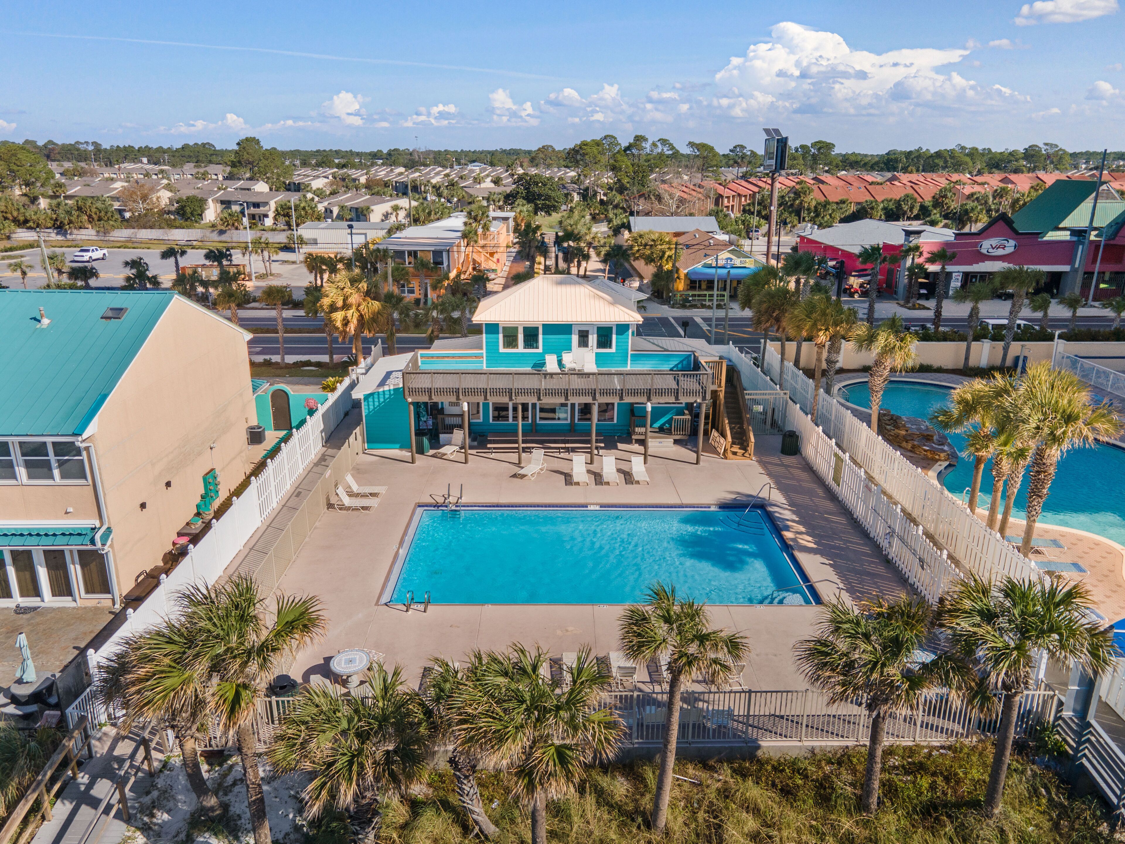 Ein Resort mit großem Pool, Liegestühlen und einem Gebäude mit blauem Dach.