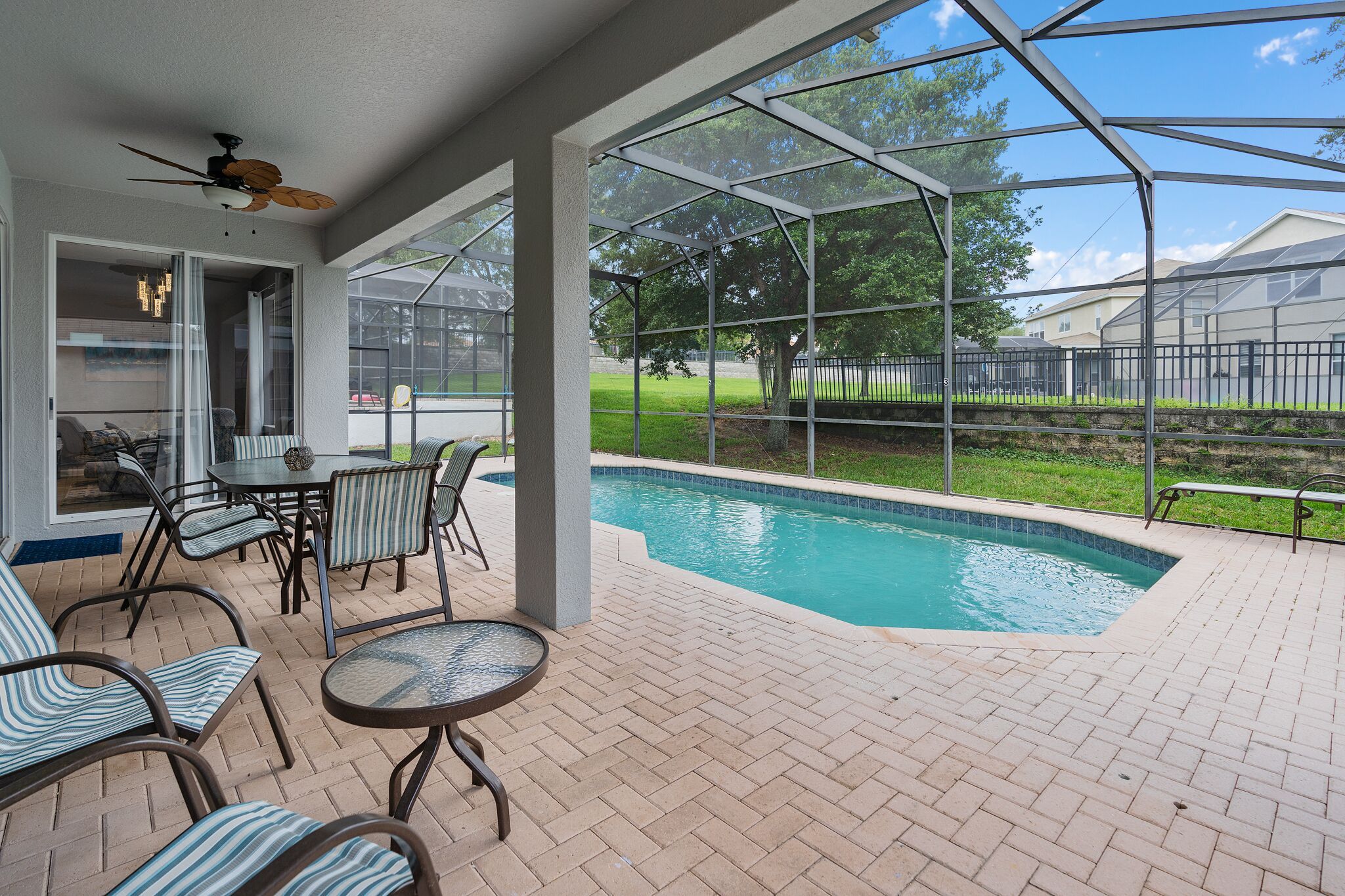 A covered patio area with a pool, outdoor furniture, and a view of the surrounding landscape.