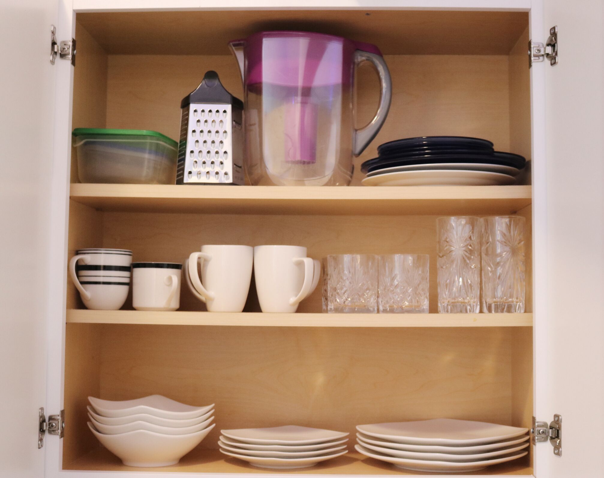 Un meuble de cuisine contenant des ustensiles, des tasses et des assiettes.