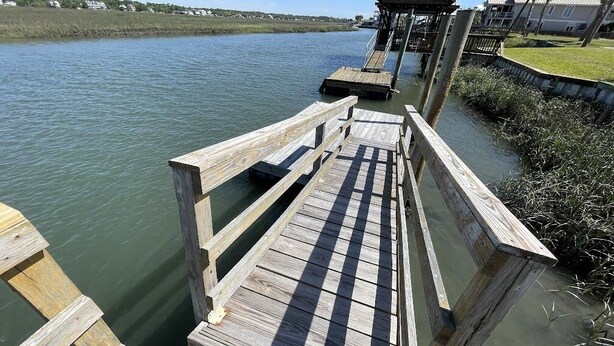 Een houten steiger die zich uitstrekt over een rustig wateroppervlak, met een overdekte constructie aan het einde.