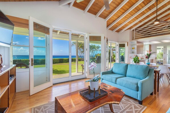 A spacious living area with a large sliding glass door leading to a balcony, a blue sofa, and a wooden coffee table.