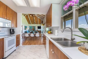 A modern kitchen with wooden cabinets, a white countertop, and a stainless steel sink.