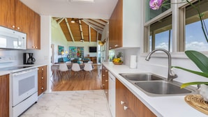 A modern kitchen with wooden cabinets, a white countertop, and a stainless steel sink. - Modern Home with Hot Tub, AC & Ocean Views! (Po'ipu)