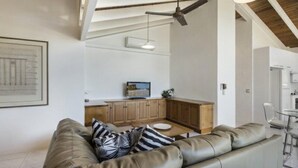 Una sala moderna con un sofá de cuero, armarios de madera y un comedor.