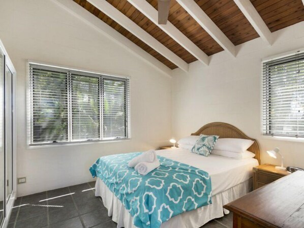 A bedroom with a bed, two bedside tables, a nightstand, and a window with blinds. - Descola 10 - On Noosa Hill this top-level unit with ocean views from the balcony (Noosa)