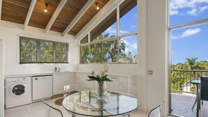 Una cocina moderna con una mesa de vidrio, armarios blancos y vistas al exterior.