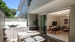 Un patio al aire libre con mesa, sillas y banca.