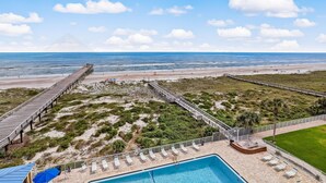A beach view with a wooden pier, a swimming pool, and lounge chairs. - 6th Floor, Updated and beautiful!  Oceanfront condo with balcony, fishing pier. (Fernandina Beach)