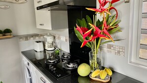A kitchen with a gas stove, a coffee maker, a toaster, and a vase with flowers.