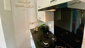 A modern kitchen with white cabinets, a black stove, and decorative fishbones on the wall.