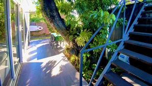A patio area with a table and chairs, a surfboard, and a staircase leading to an upper level.